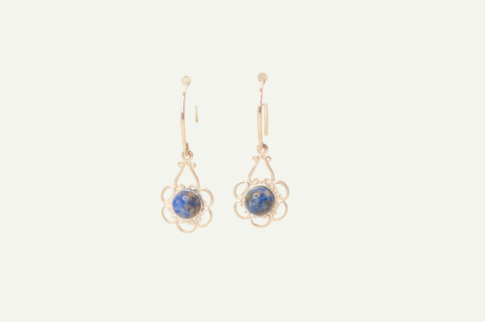 Pair of earrings with blue lapis gemstones on a beige background