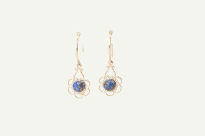 Pair of earrings with blue lapis gemstones on a beige background
