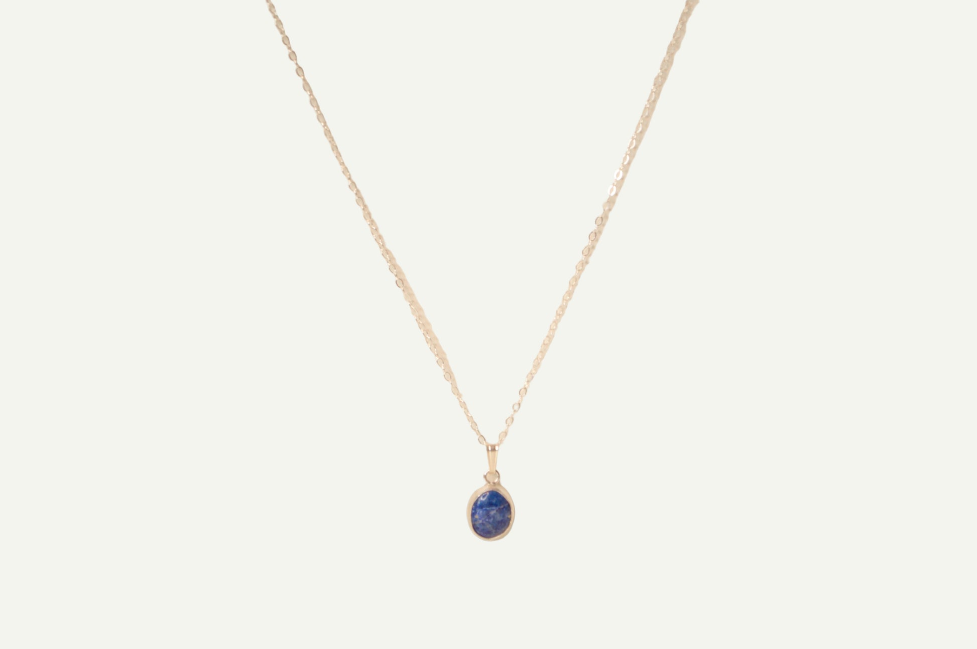 Necklace with a blue lapis pendant on a beige background