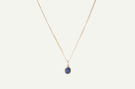 Necklace with a blue lapis pendant on a beige background