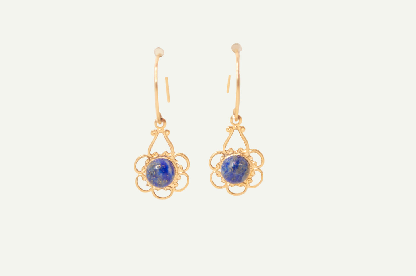 Gold earrings with blue lapis gemstones on a beige background