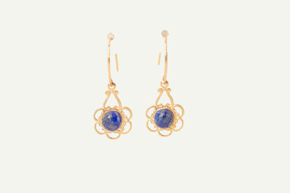 Gold earrings with blue lapis gemstones on a beige background