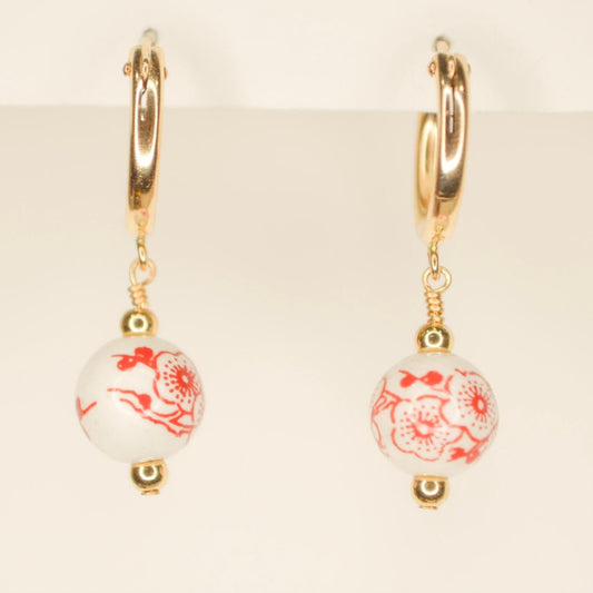 Gold hoop earring with red and white flower bead