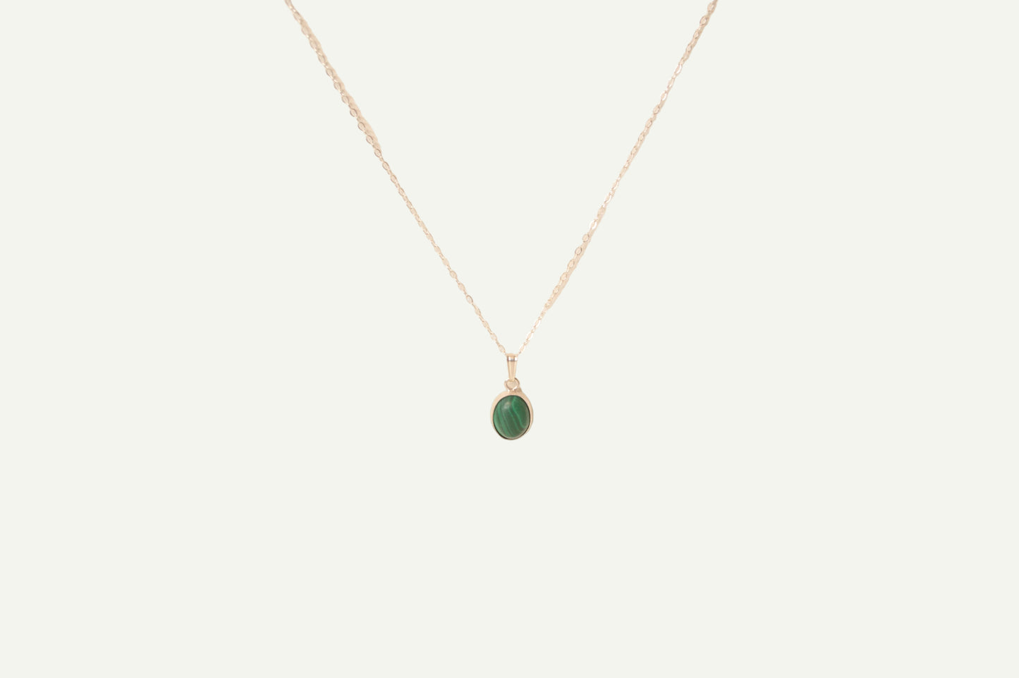 Necklace with a green malachite pendant on a beige background