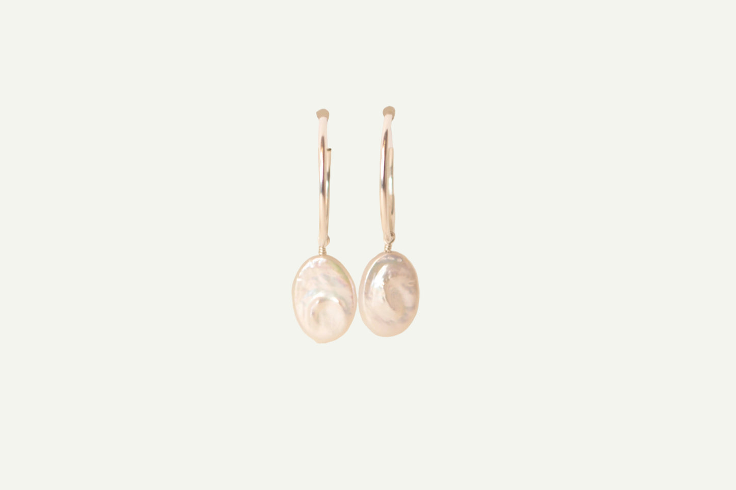 Pair of oval pearl earrings on a beige background