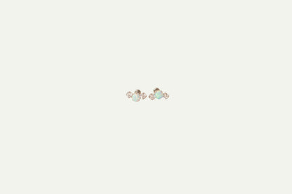 Pair of silver flatback earrings with Opal and crystals on a beige background