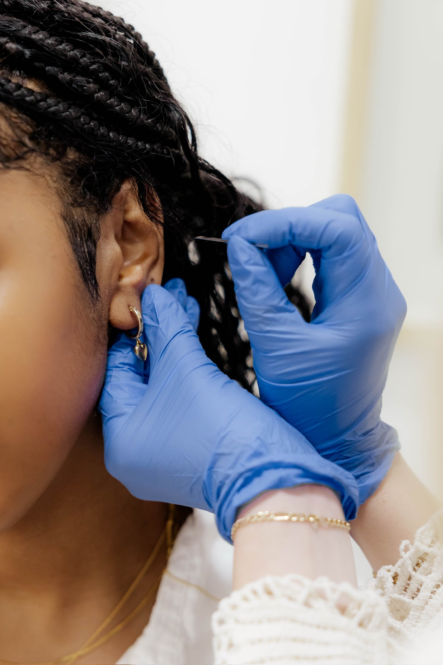 Person getting a piercing by piercer wearing gloves 