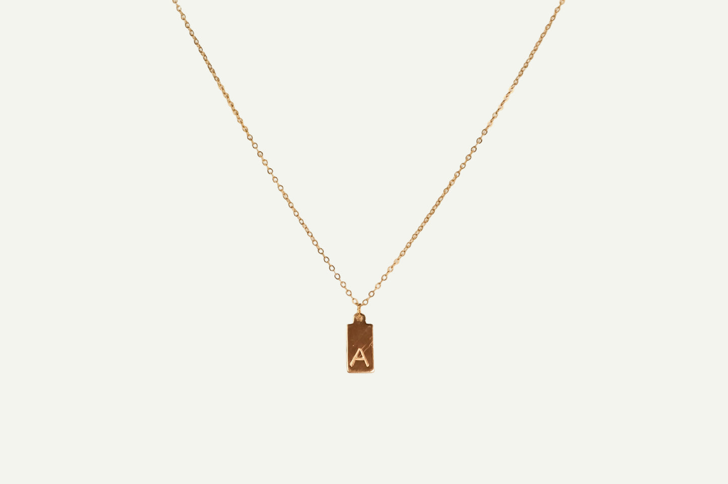 Gold necklace with a pendant featuring the letter 'A' on a white background